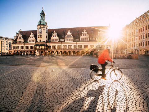 Tagung & Konferenz Leipzig Convention: Über den Marktplatz mit Altem Rathaus fährt eine Fahrradfahrerin