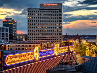 Das Foto zeigt die erleuchtete Innenstadt am Abend mit dem Westin Leipzig im Hintergrund.