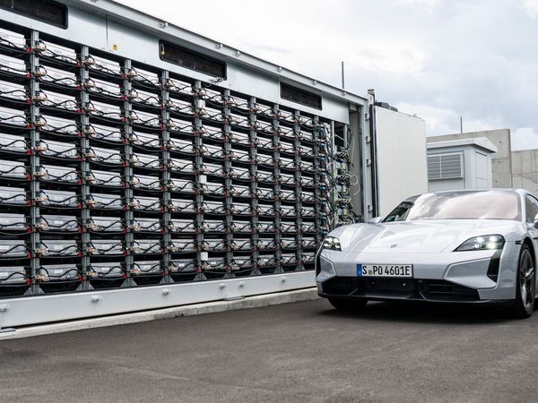 Batteriespeicher aus gebrauchten Taycan-Batterien, davor steht ein Auto von Porsche
